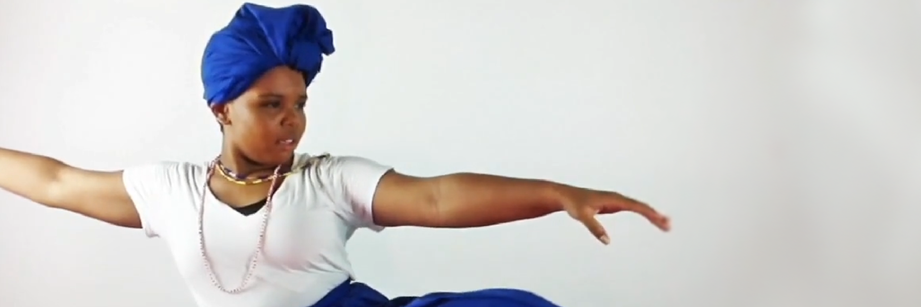 a woman in a white t-shirt and a blue headwrap dances